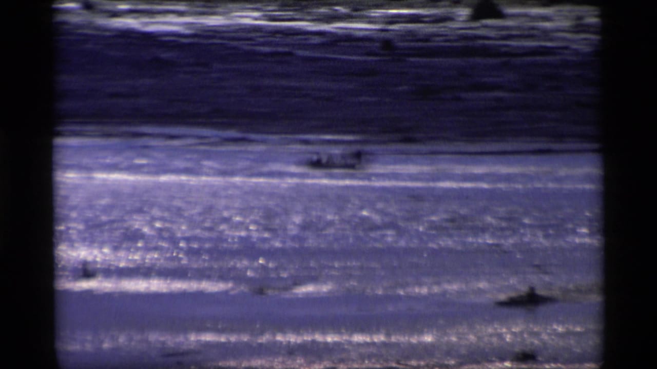 Small boat crossing bright, shimmering water with dark shoreline bands behind it.