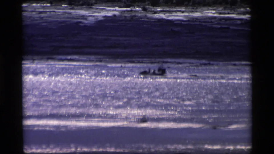 1977 Alaska 8mm frame with small motorboats on glittering water, possibly carrying people too distant to identify.