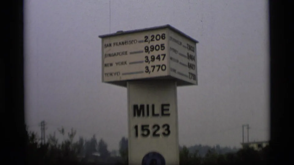 1977 Alaska frame of the mile 1523 marker, with readable distance names on a box sign above the post.