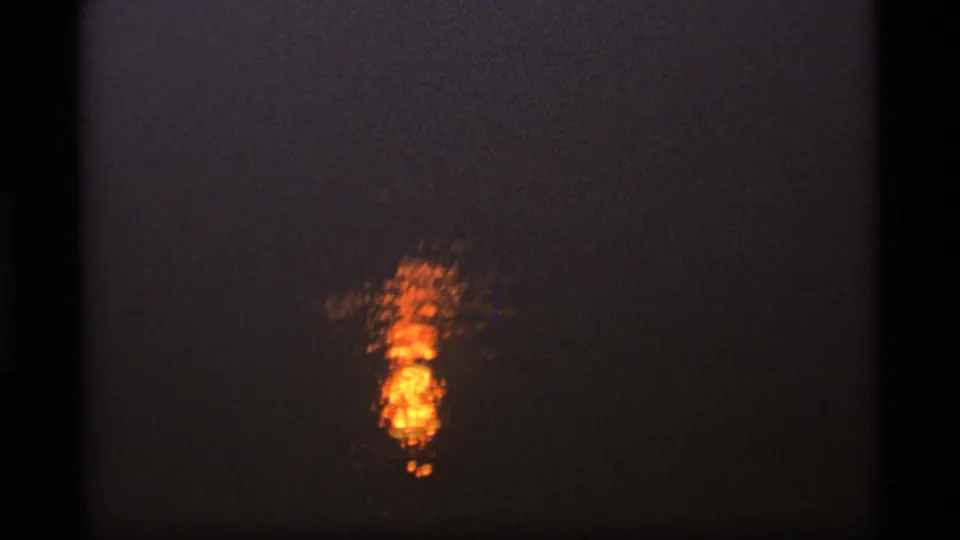 Close view of a warm sun reflection on dark water in archival 8mm footage.