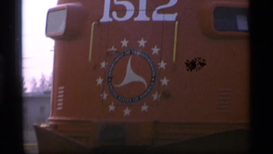 A tighter home-movie frame shows the yellow locomotive's number 1512 above a circular star emblem, with soft focus and film dust visible.