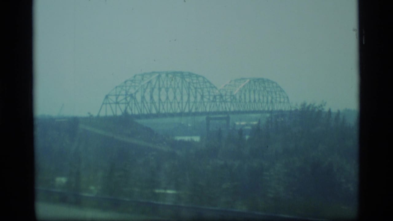 Distant steel truss bridge over a hazy river landscape.