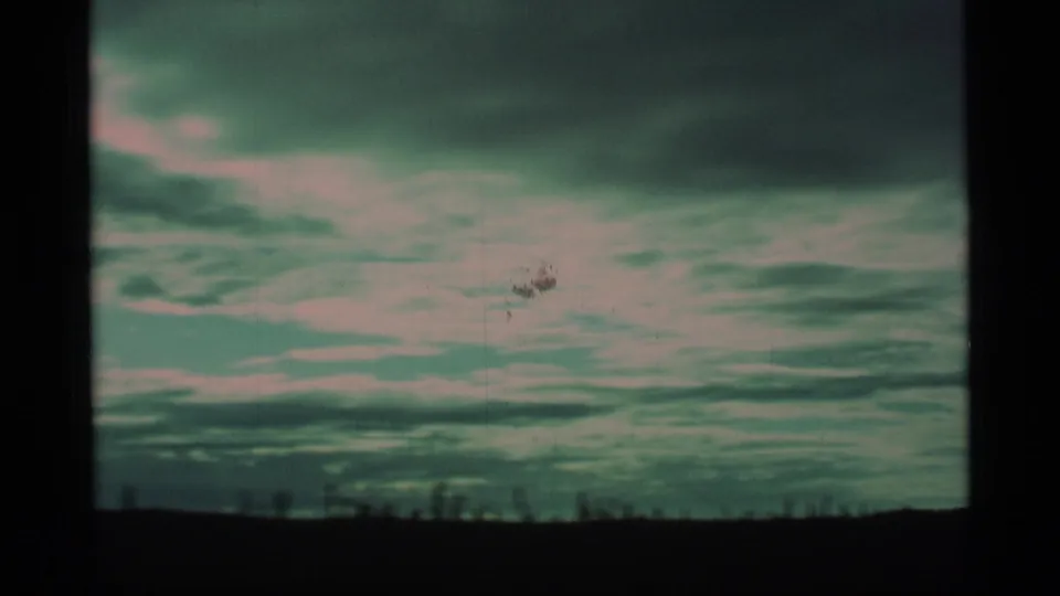 1977 Alaska 8mm frame showing layered cloud cover and a low dark horizon with visible film wear.