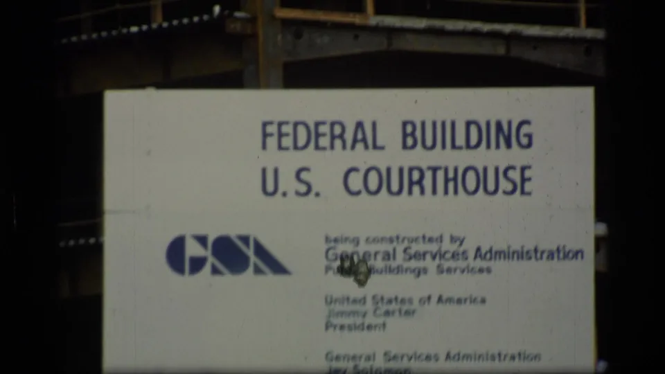 Sign for a Federal Building and U.S. Courthouse in Alaska, with GSA logo and construction text visible on 8mm film.