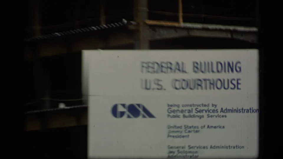 Archival 8mm view of the Federal Building U.S. Courthouse sign with GSA logo and surrounding construction structure.