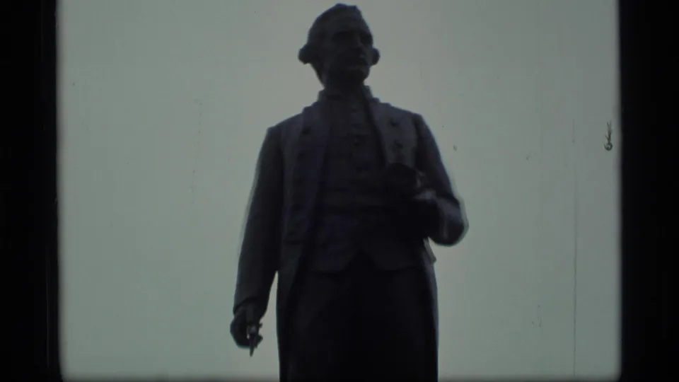 Close 8mm view of a silhouetted public statue, likely in Alaska based on clip metadata.