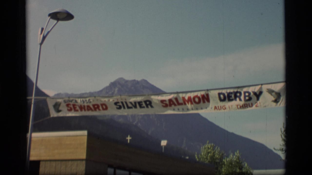 1977 Alaska home-movie view of the Seward Silver Salmon Derby banner crossing the frame below distant mountains.