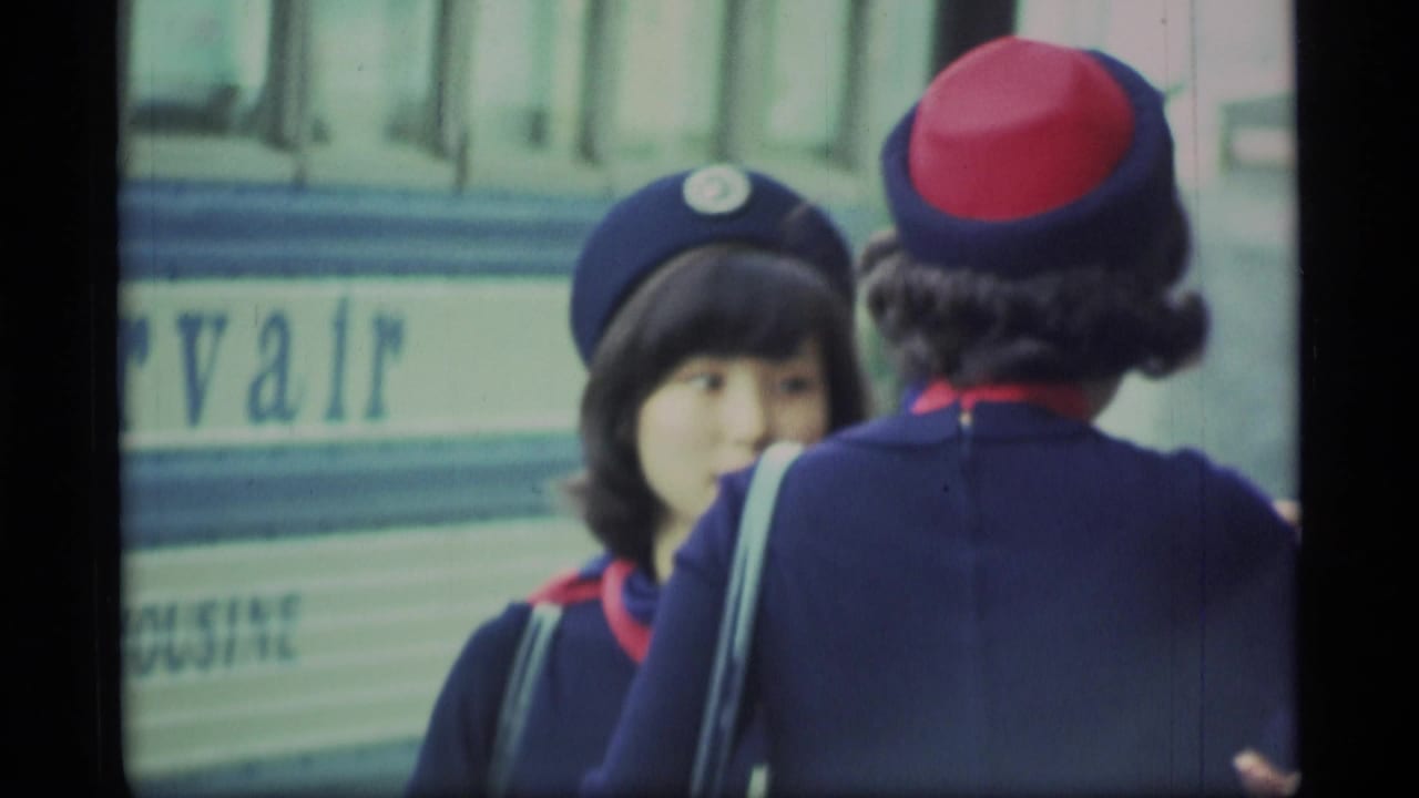 In this 1977 Alaska 8mm frame, two uniformed women appear near a vehicle with partial lettering, one facing the camera and one turned away.