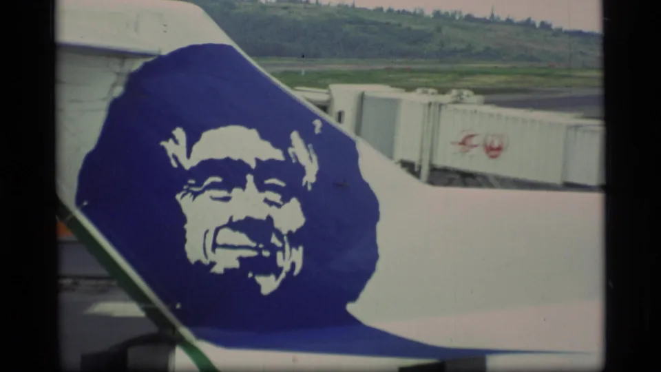 Close view of an Alaska Airlines Boeing 727 tail logo at an airport terminal in 1977 8mm footage.