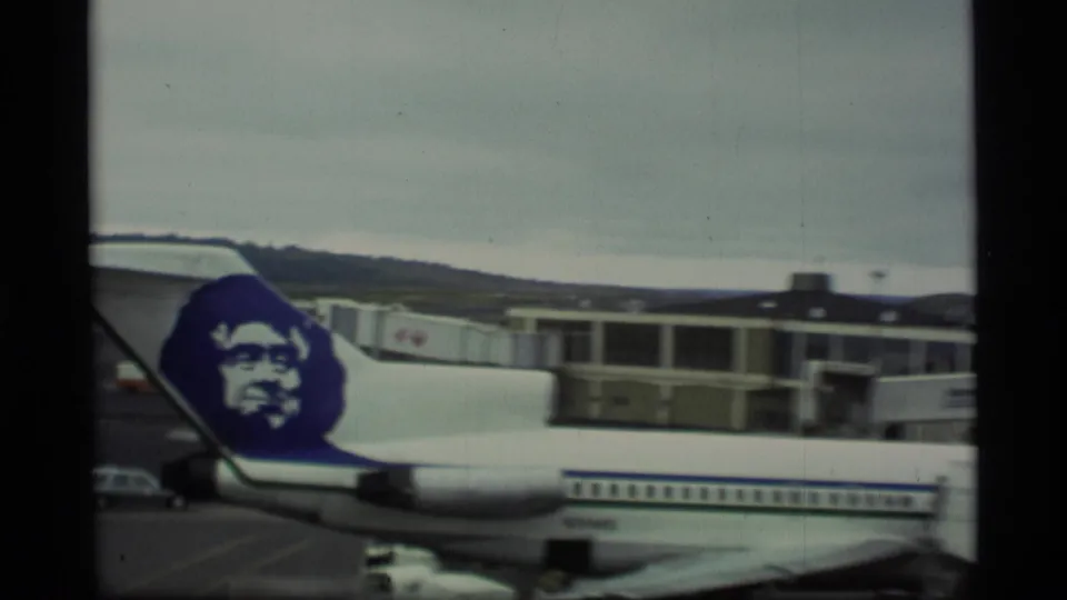 Alaska Airlines Boeing 727 at an airport gate in Alaska 1977 footage, with terminal windows and ground equipment visible.