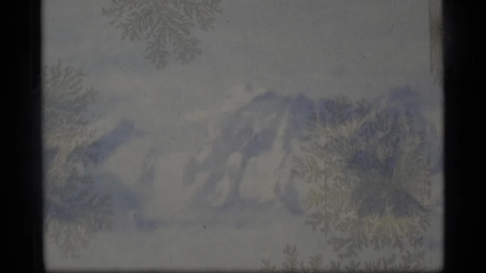 1977 Alaska 8mm view of distant snow-covered mountains, softened by crystalline film texture and muted blue-gray color.