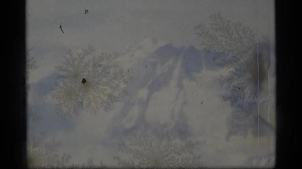 1977 Alaska 8mm frame showing indistinct snowy peaks and crystalline surface patterns across a pale winter landscape.