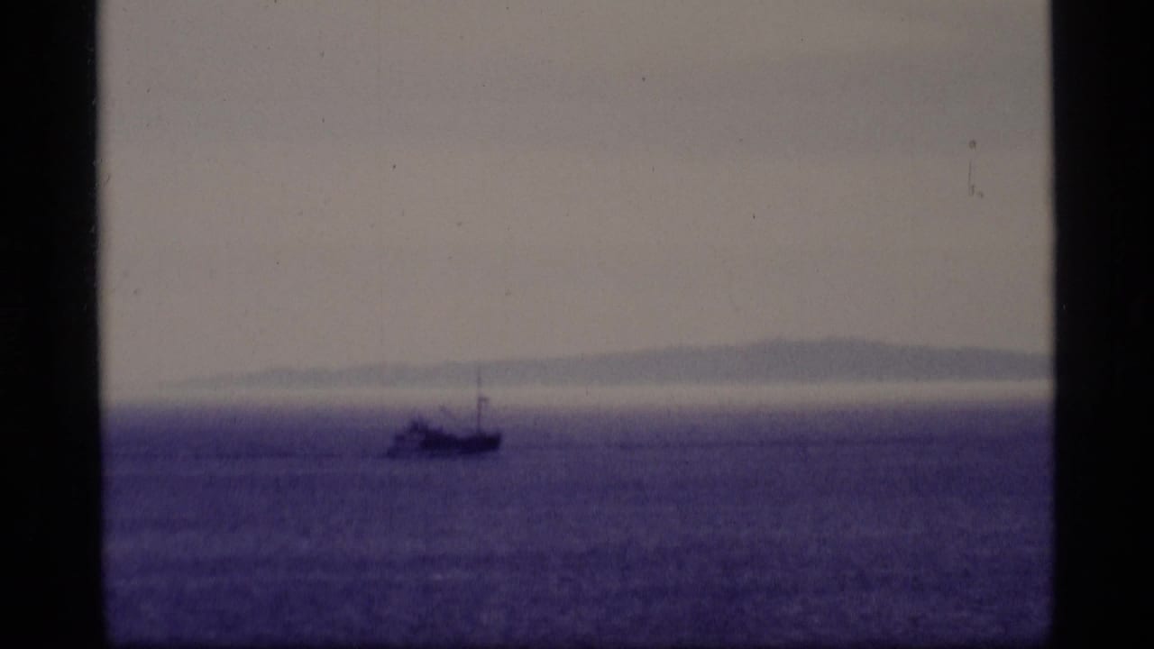 Distant vessel on open water with a faint landmass in the background.