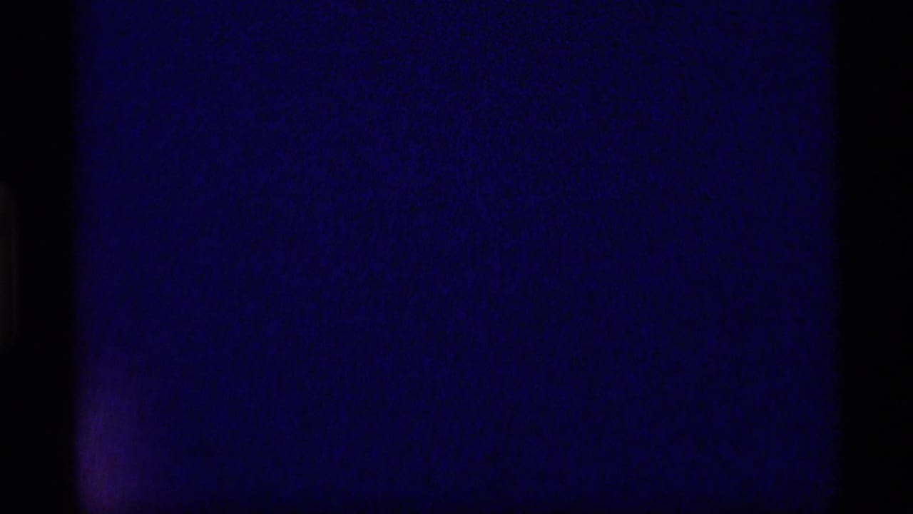 Blue-black 8mm frame at the start of a 1977 Alaska home-movie clip, showing mostly leader-like darkness and film edges.