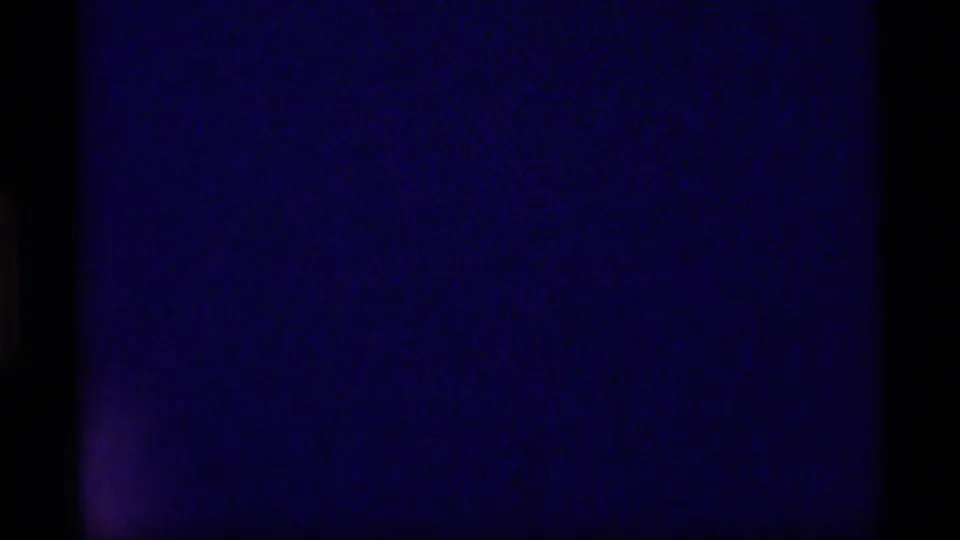 Blue-black 8mm frame at the start of a 1977 Alaska home-movie clip, showing mostly leader-like darkness and film edges.