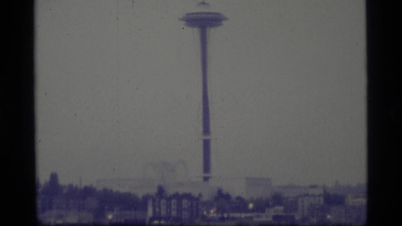 Hazy city skyline with a tall observation tower rising above low buildings.