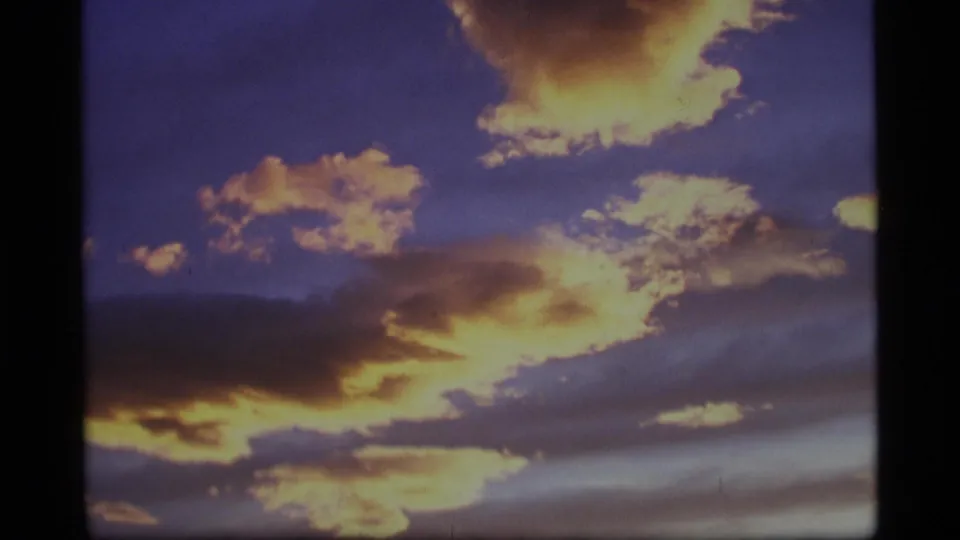 1977 Alaska 8mm frame showing a wider sunset cloudscape above a dark horizon line.