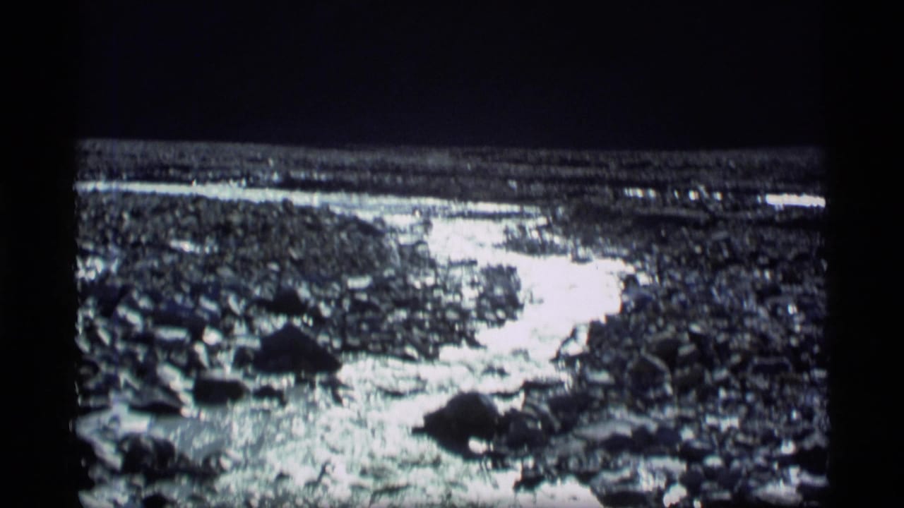 Reflective stream water running across rocks and gravel in a wide view.