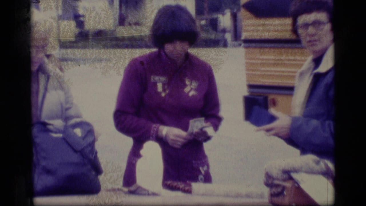 Woman in purple jacket counts money near a bus while another visitor holds a wallet.
