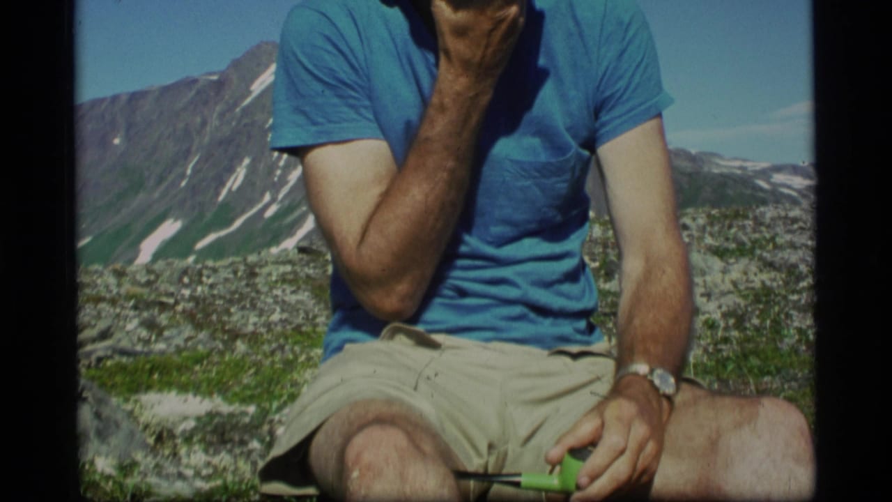 The 1977 Alaska frame shows a man seated outdoors, cropped at the face, with a pipe in hand and alpine peaks behind him.
