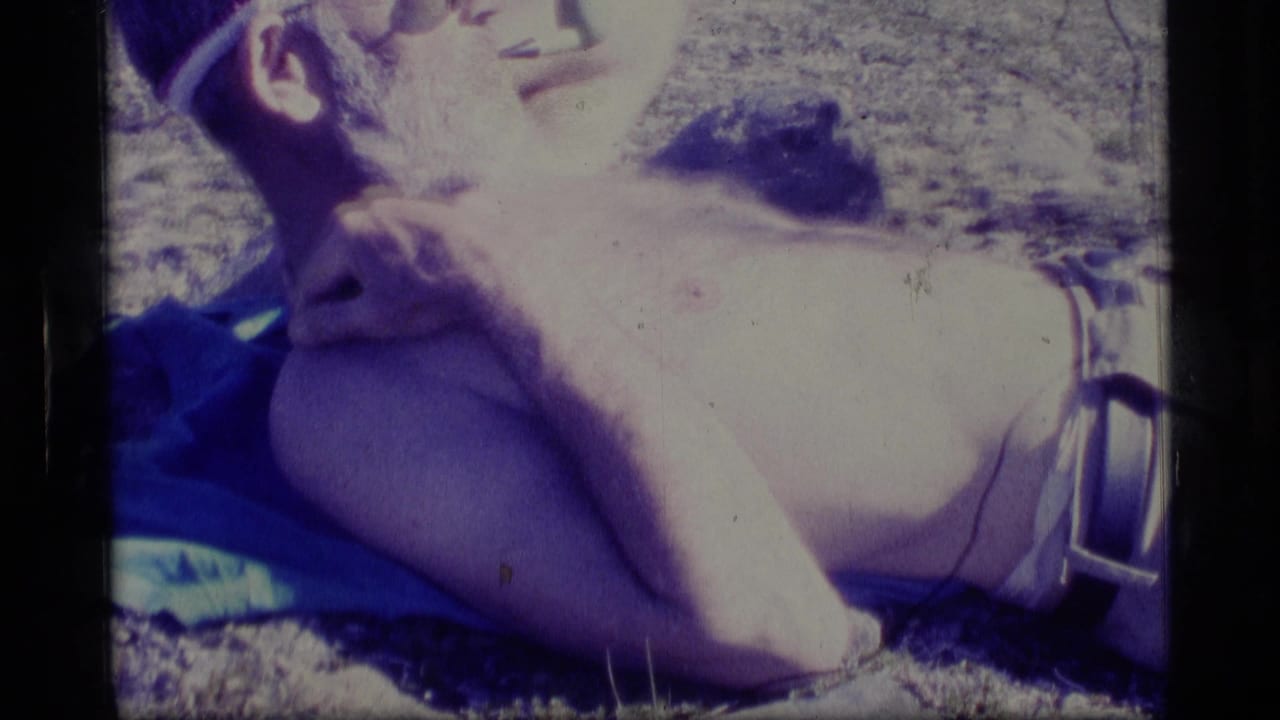 Man reclining on a towel with his hand near his neck.