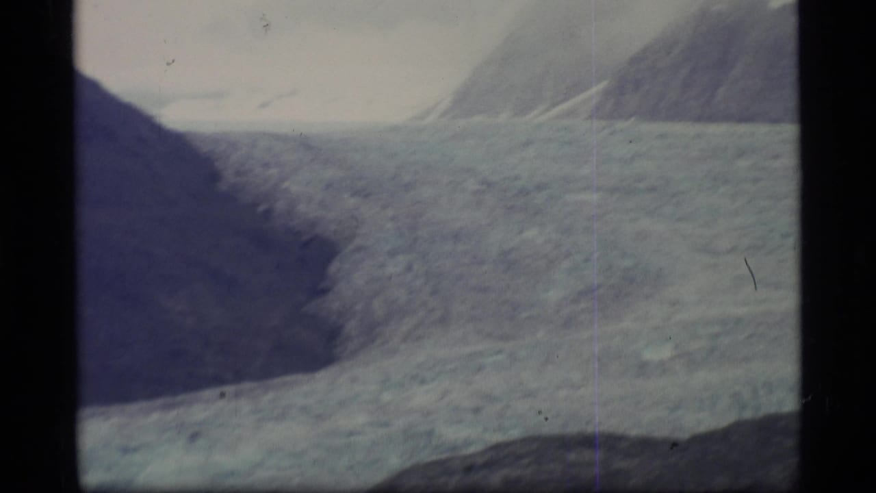 1977 Alaska 8mm view of a glacier and surrounding mountain walls, with scratches and soft exposure from the film scan.