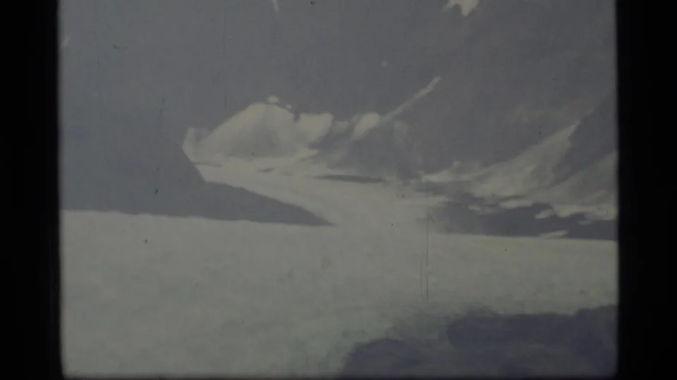 1977 Alaska 8mm frame showing glacier ice and a snow-streaked mountain ridge with soft exposure and visible film grain.