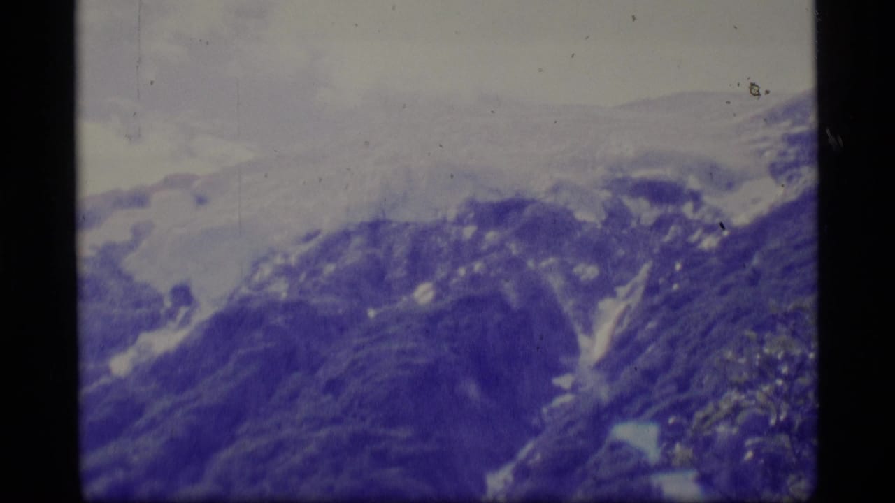 Blue-toned mountain ridge with snow patches and pale cloud cover.