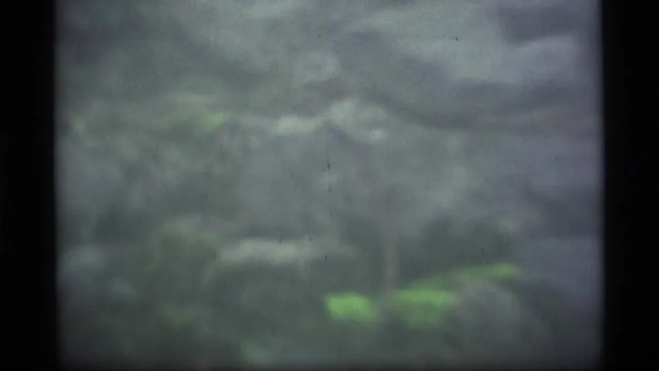 Soft 8mm view of an Alaskan rocky ground surface with faint green moss and visible frame edges from the 1977 home movie.