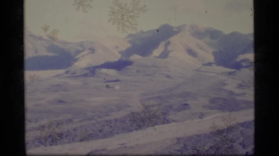 Snowy Alaska mountain landscape appears in faded 1977 8mm footage with visible surface marks.