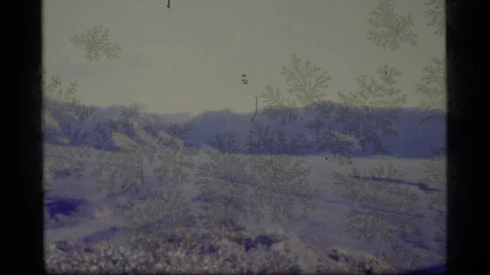 1977 Alaska 8mm view of a snowy valley and distant ridge, with frost-like patterns, scratches, and aged blue-purple color.