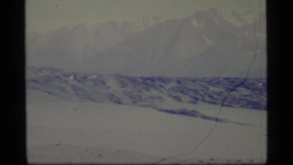 1977 Alaska 8mm still showing blue-toned snow, a distant mountain line, and soft exposure from original home-movie film.