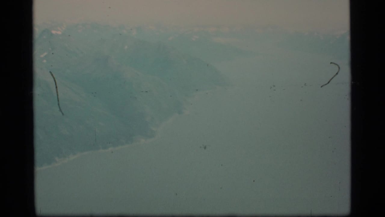 Pale snowy mountain landscape with dark 8mm frame borders and film surface marks.