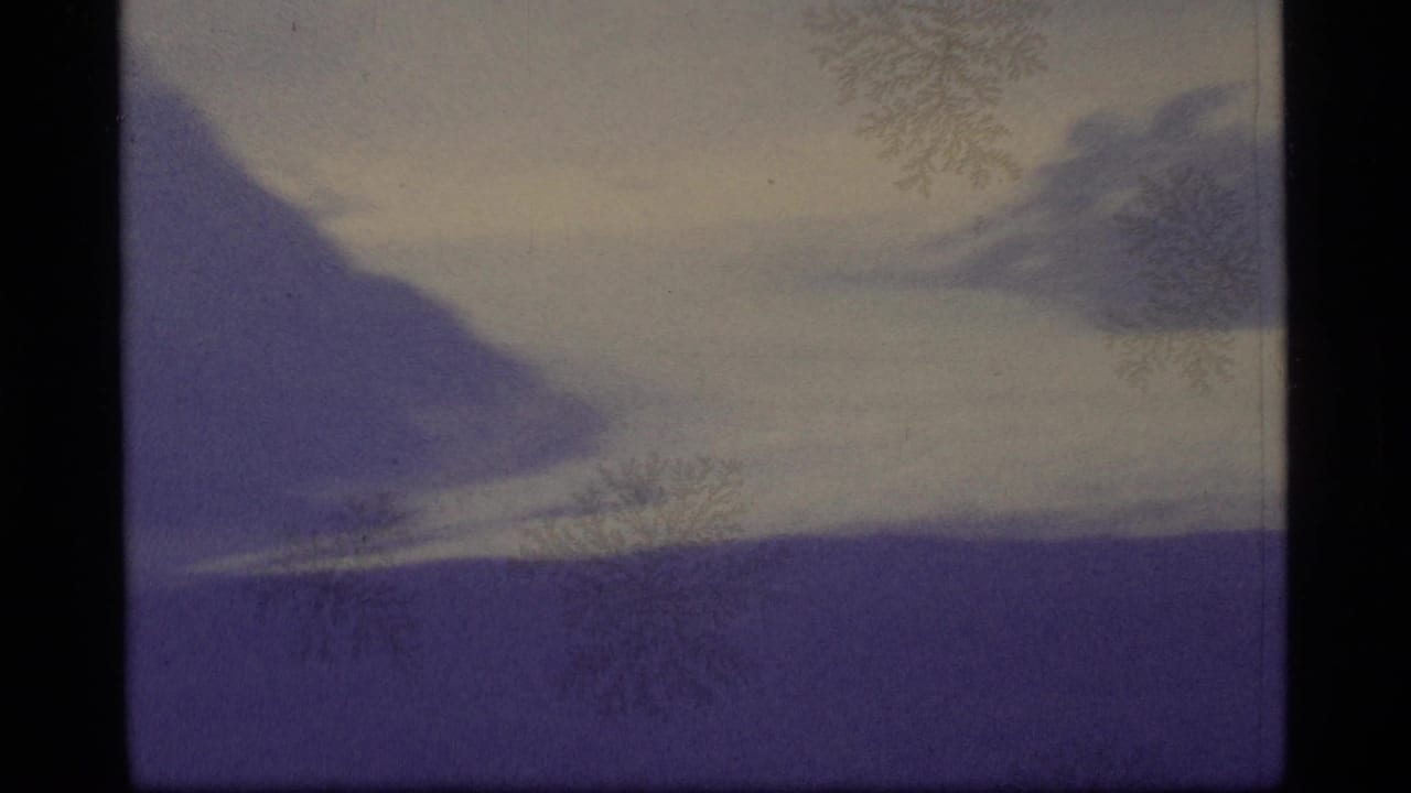 1977 Alaska 8mm frame showing a snowy mountain slope under fog, with purple color shift, dark frame edge, and frost-like surface marks.