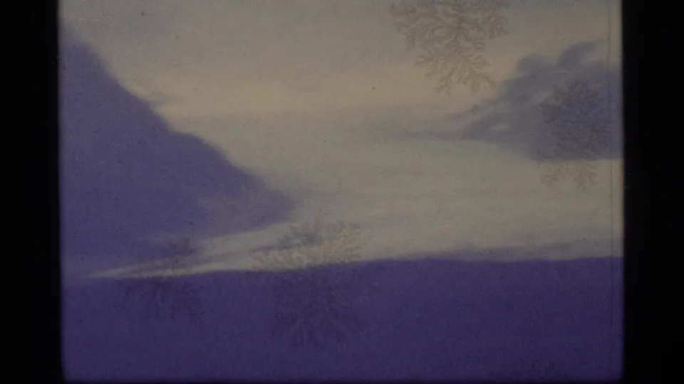 1977 Alaska 8mm frame showing a snowy mountain slope under fog, with purple color shift, dark frame edge, and frost-like surface marks.