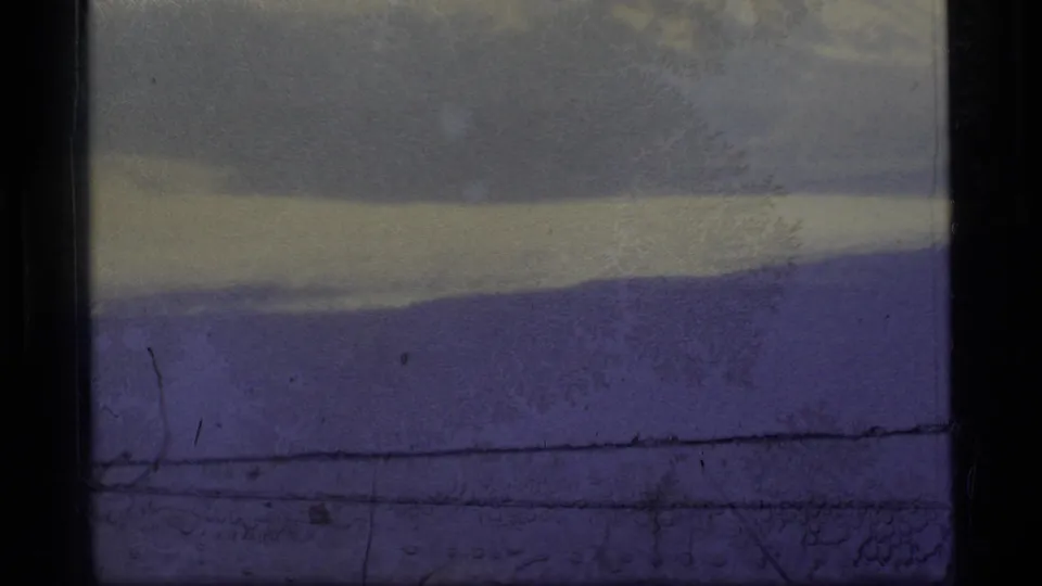 1977 Alaska 8mm frame of a low snowy mountain horizon under fog, with visible scratches, dark borders, and purple film color shift.