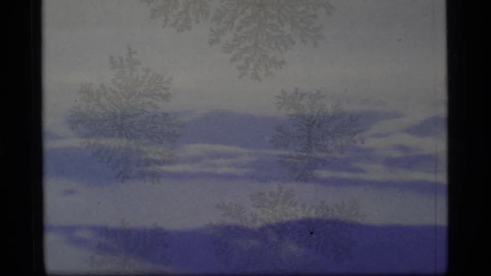 1977 8mm Alaska winter view with soft snowfields, blue-toned bands, faint crystal-like marks, and visible film gate borders.