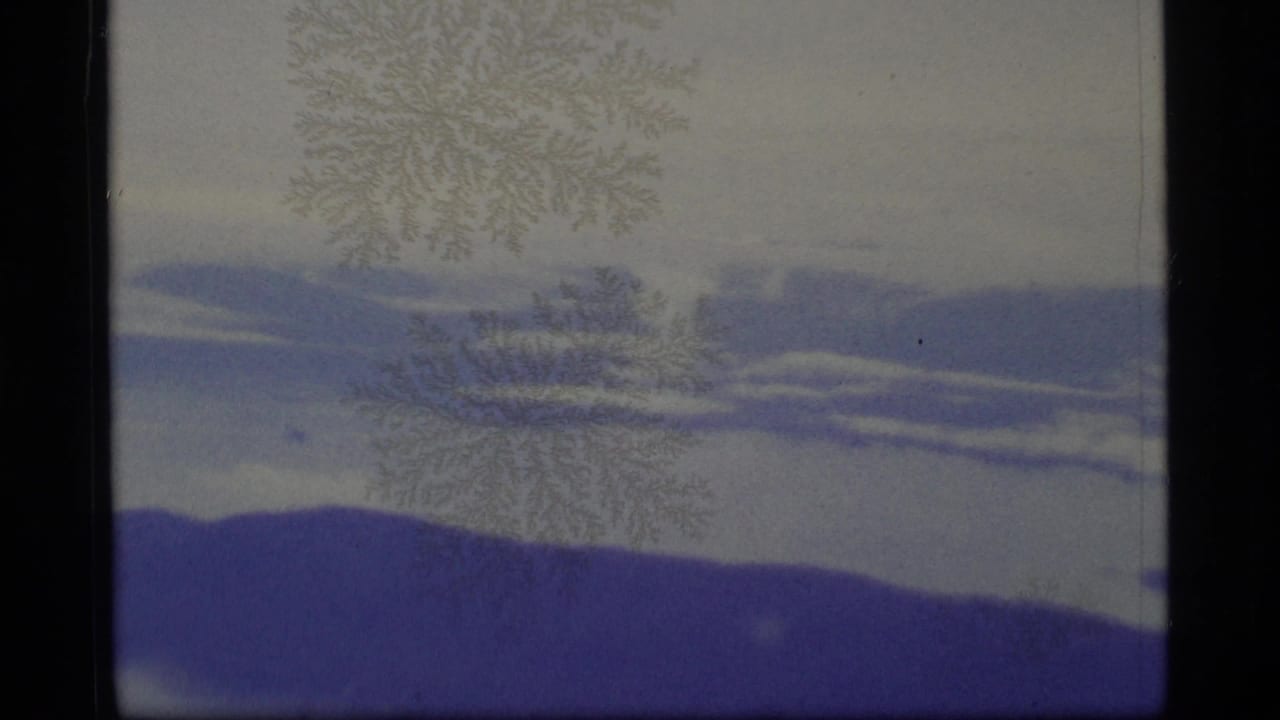 Blue-gray clouds and pale sky seen through dark 8mm frame borders.