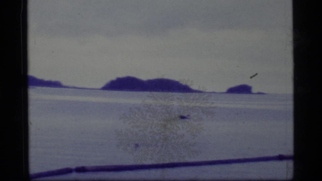 Island silhouettes and pale horizon viewed through a marked 8mm frame.