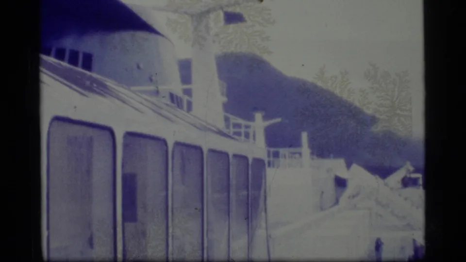 1977 Alaska 8mm frame showing the side of a boat with railings and deck structure near a snowy or icy landform.