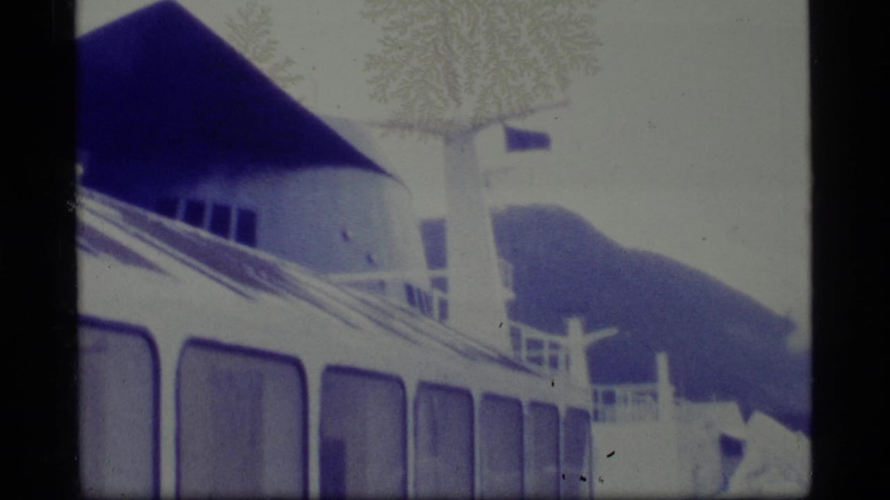 1977 Alaska 8mm frame showing part of a white ship, railings, upper deck structures, and visible dust patterns on the film.