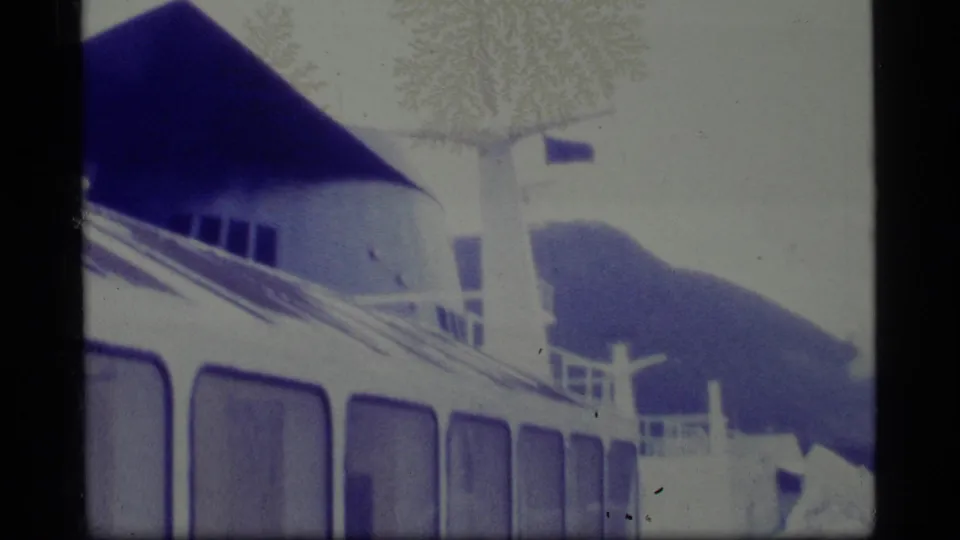 1977 Alaska 8mm frame showing part of a white ship, railings, upper deck structures, and visible dust patterns on the film.