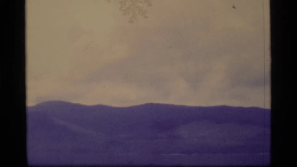1977 Alaska 8mm view of a dark mountain ridge with muted sky and soft home-movie exposure.
