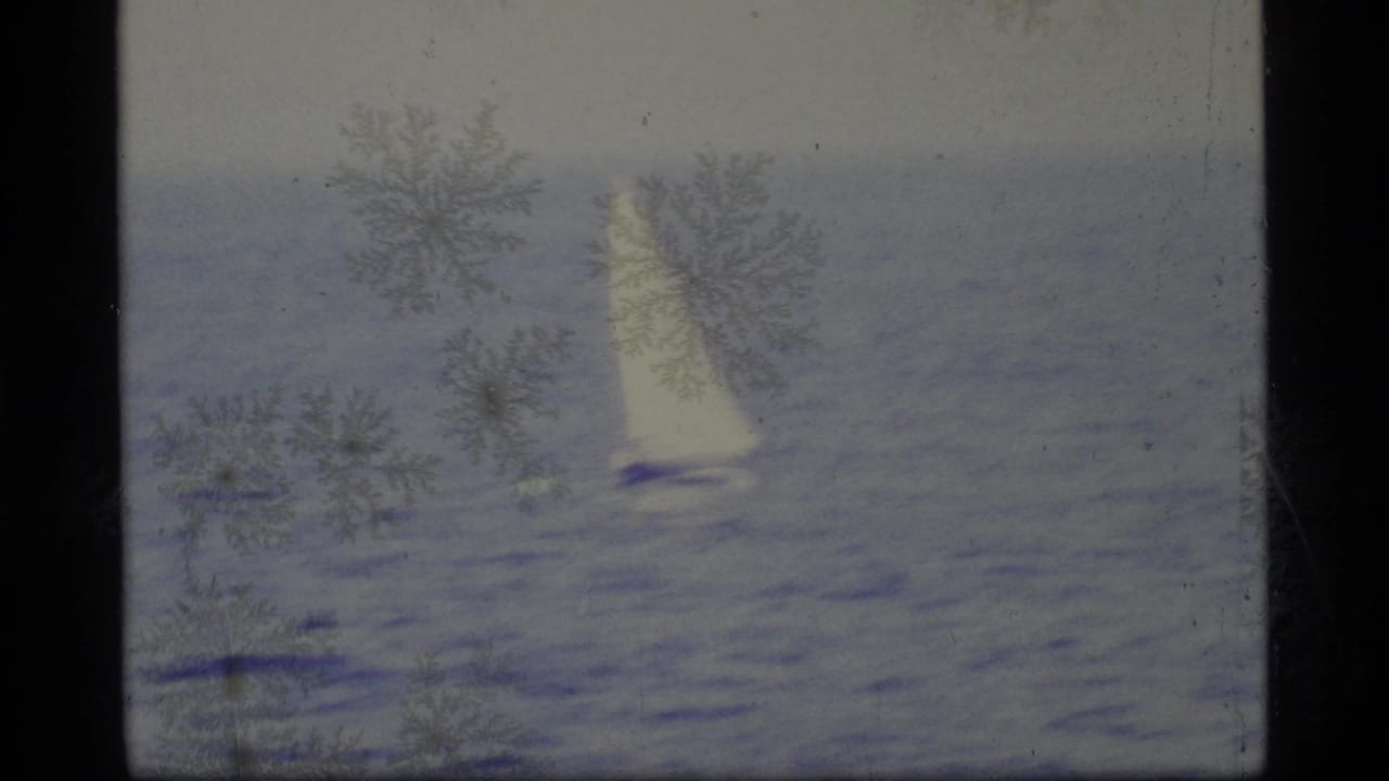 White sailboat on calm water with dark film borders and surface patterns.