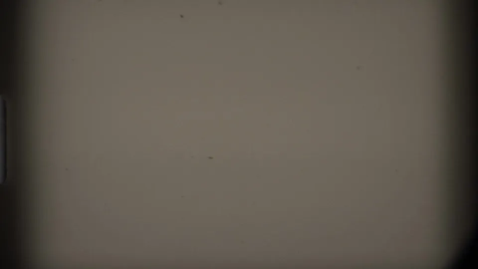 1977 Alaska 8mm frame showing a largely featureless gray field with dark gate edges, dust, and faint surface marks.