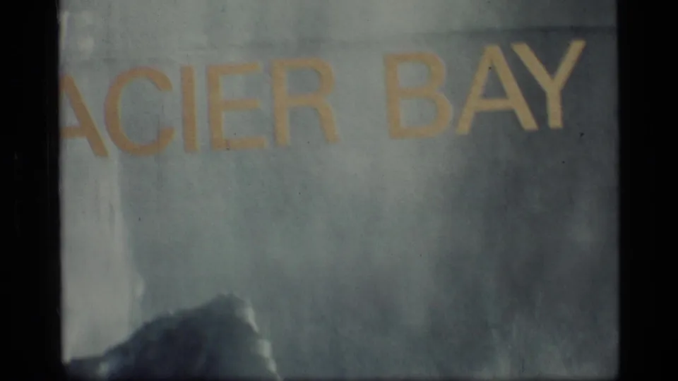 1977 Alaska home-movie frame with cropped Glacier Bay title text, soft focus, grain, and dark film borders.