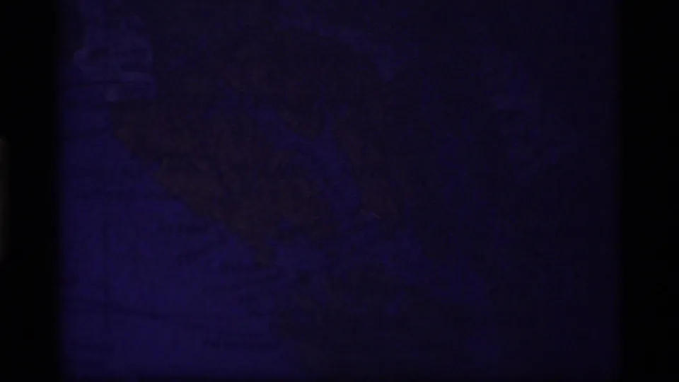 Dark 8mm transition frame with faint blue-purple exposure and little readable subject detail.