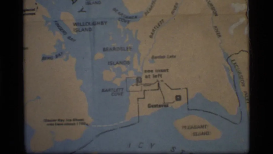 1977 8mm frame showing a Glacier Bay, Alaska map section with waterways, islands, Gustavus, and Bartlett Cove visible.