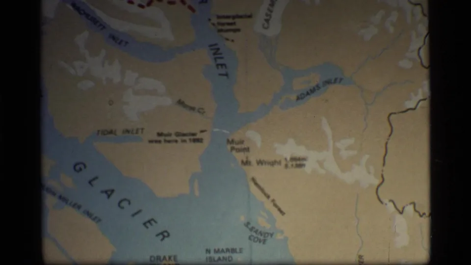 1977 8mm close-up of a Glacier Bay map with Muir Inlet, Adams Inlet, Sandy Cove, and glacier notation visible.