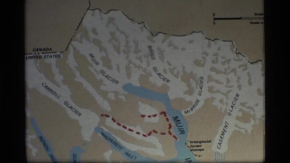 Glacier Bay map frame from the 1977 8mm clip, showing labeled glaciers and a red dashed route through the mapped area.